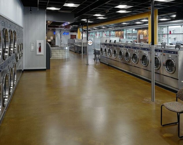 The inside of a laundromat, with rows of front-loading washers along both walls